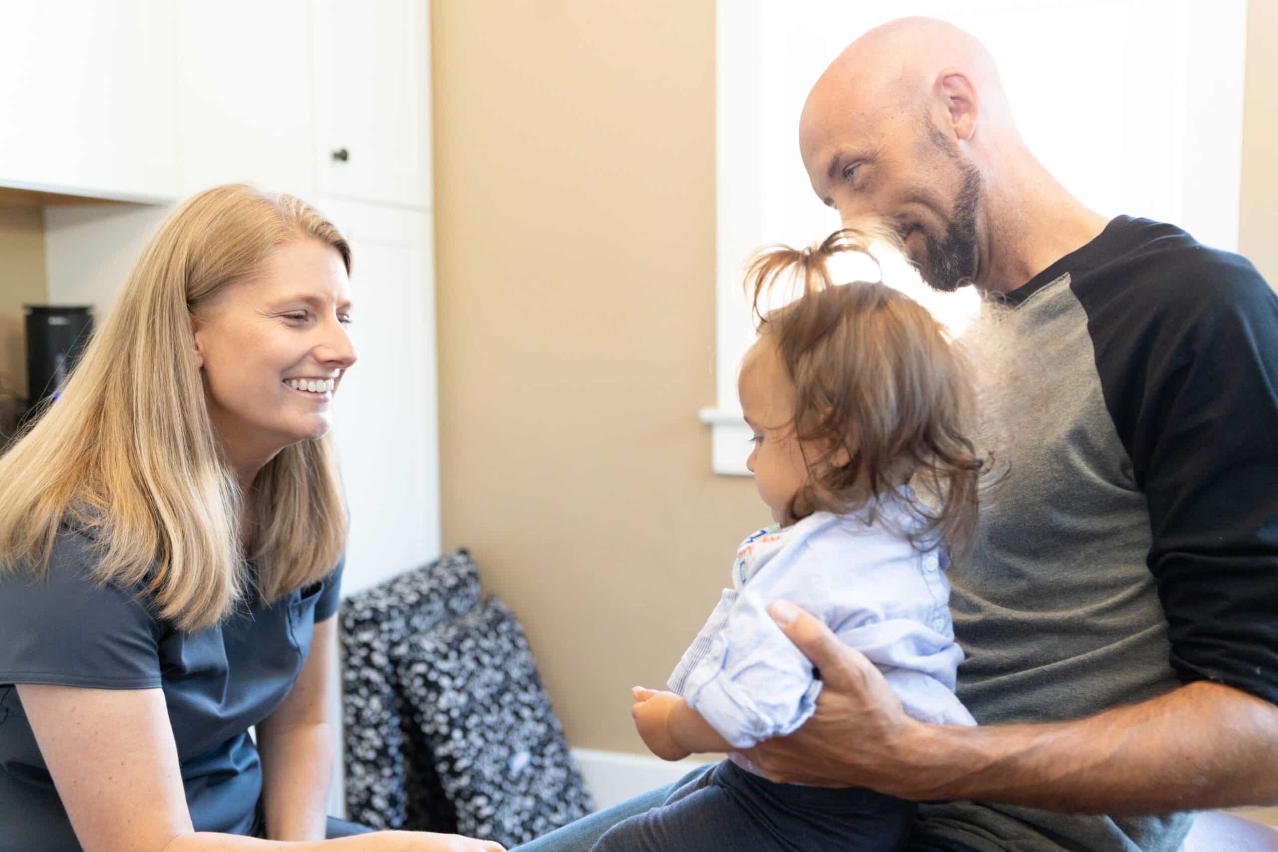 Dr. Colleen consulting with father and young patient on a pediatric chiropractic care plan.