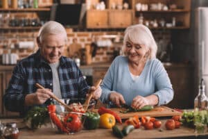 Man and woman happily chopping fresh vegetables