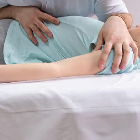 An osteopathic doctor is working with the child. Work on twisting the spine. Teenage girl patient chiropractor. Posture correction.